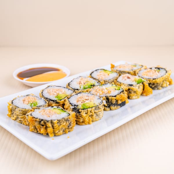 Crispy fried sushi rolls with avocado and salmon on a white plate, with dipping sauces.